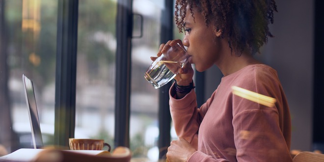side view of one pretty young black woman study working indoor with laptop drinking water side view of one pretty young black woman study working indoor with laptop drinking water