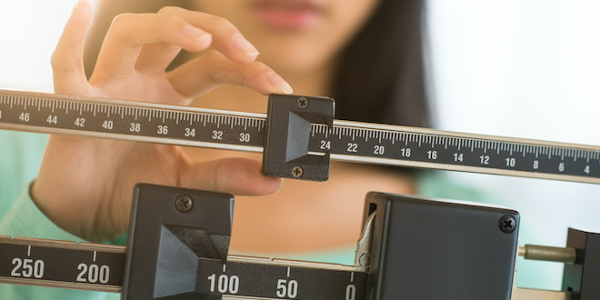 Midsection Of Woman Adjusting Weight Scale Midsection of mid adult Asian woman adjusting balance weight scale